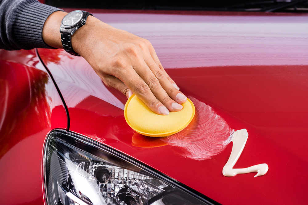 A hand putting wax on a car